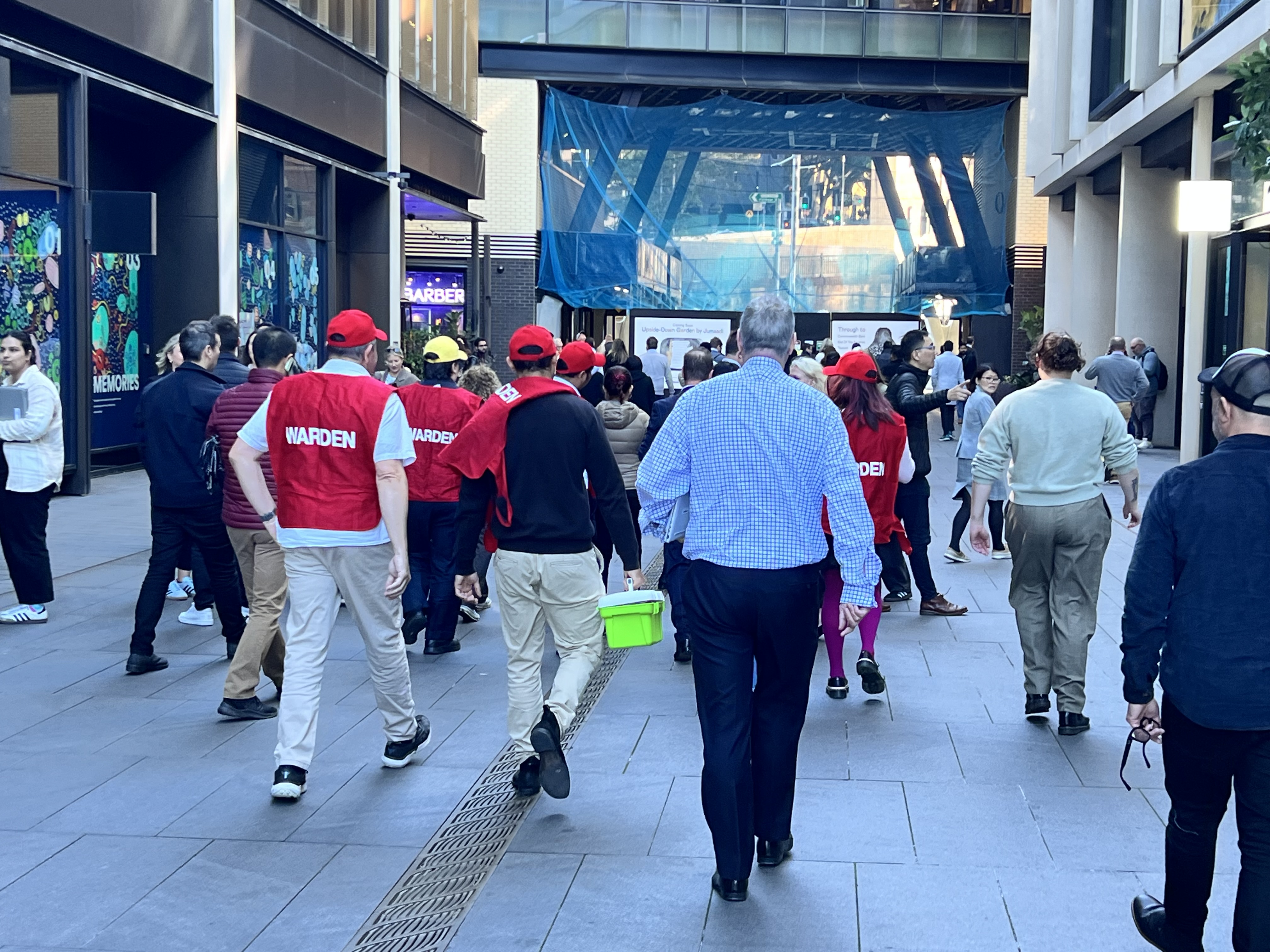 Wardens in red vests leading staff along a city laneway during an evacuation