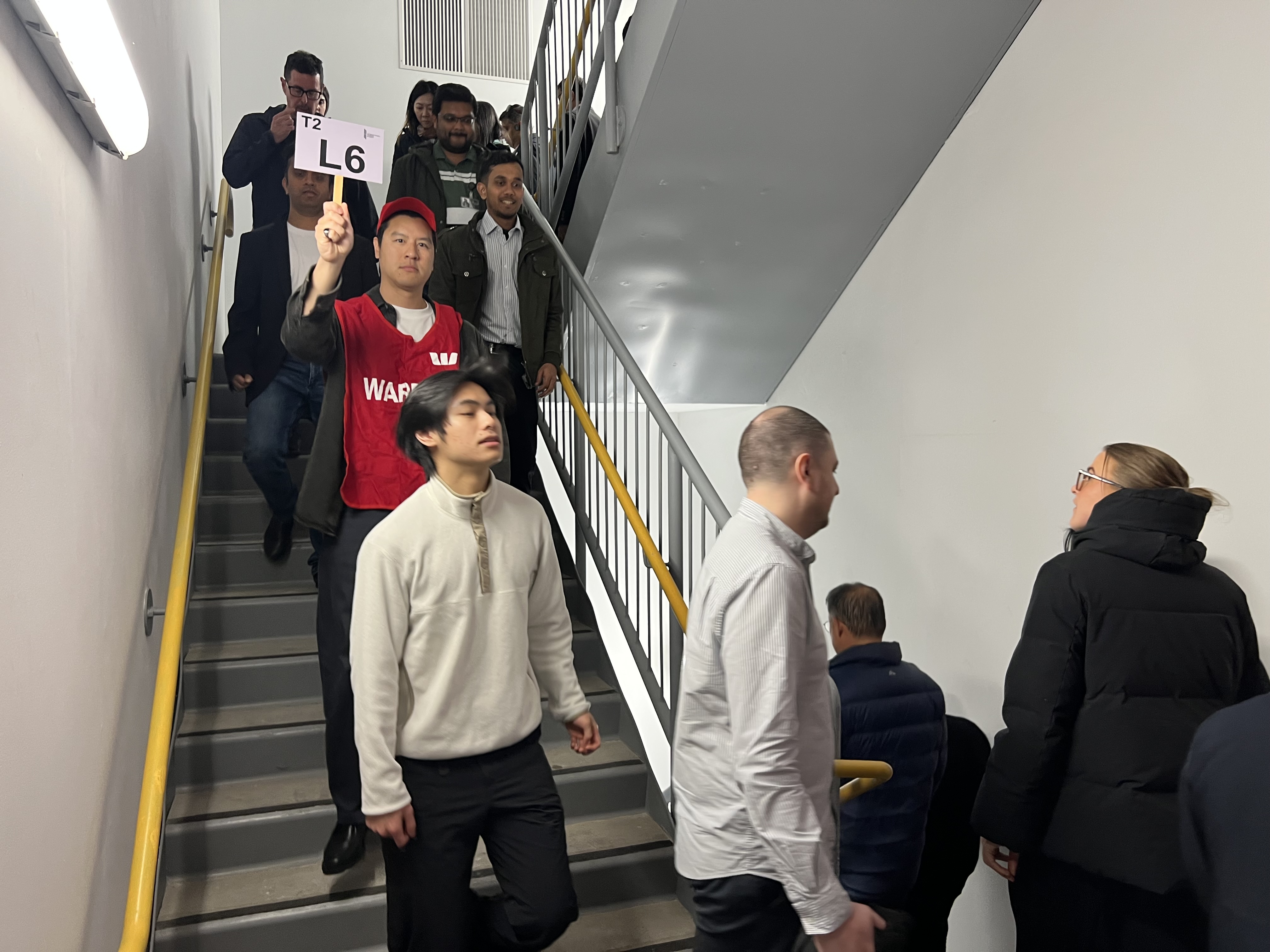 Wardens in red vests leading staff down a fire stairwell during an evacuation drill