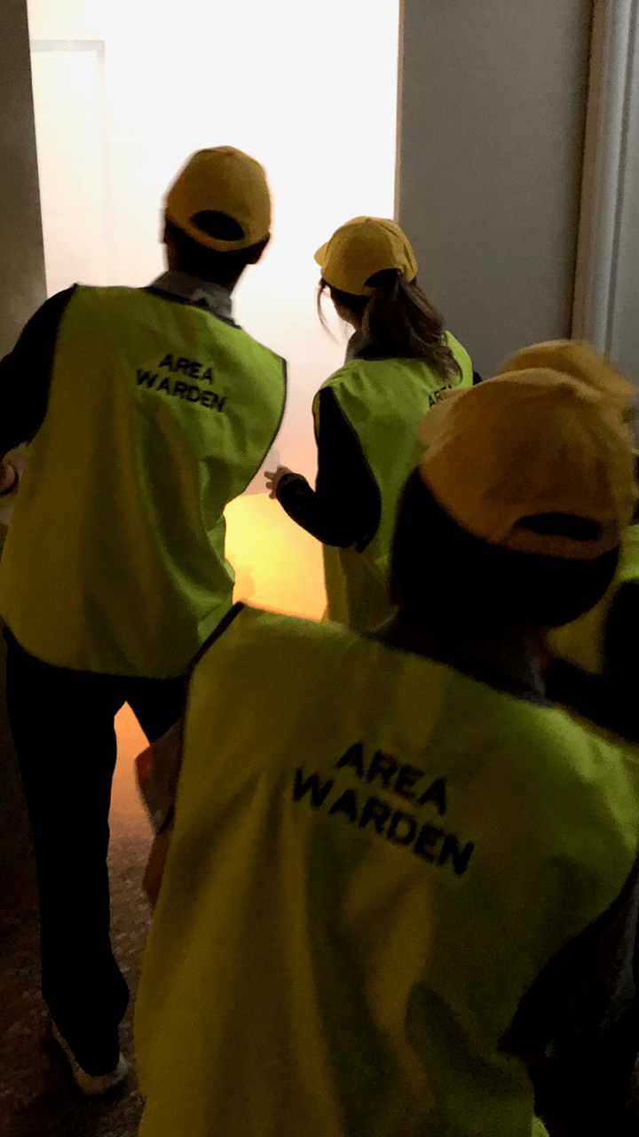 Area wardens in yellow vests and caps sweeping a floor