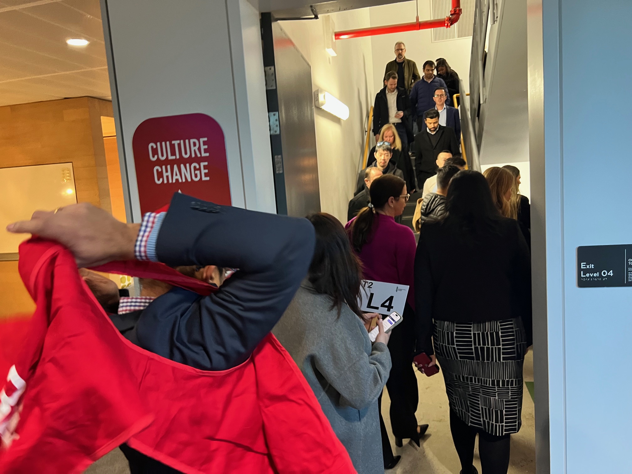 Staff filing down a fire stairwell as a warden puts on a red vest